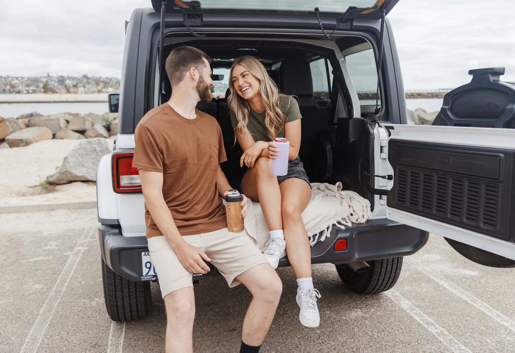 Friends enjoying drinks beside an off-road vehicle